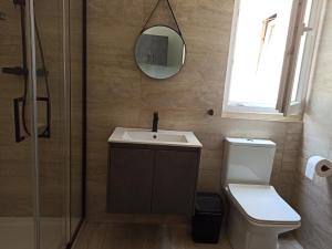 een badkamer met een wastafel, een toilet en een spiegel bij Beautiful 1-Bed Apartment in Hal Qormi in Qormi