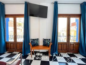 a room with blue curtains and a chair and a tv at Micaela Charming Hostal in Torremolinos