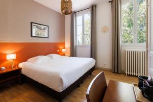 a bedroom with a large bed and two windows at Villa Sainte Anne in Porquerolles