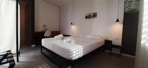 Schlafzimmer mit einem Bett mit weißer Bettwäsche und Kissen in der Unterkunft Patio 101 in San Vito lo Capo