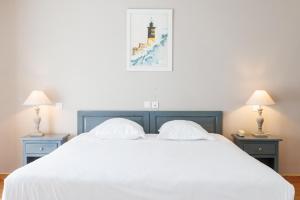 a bedroom with a large white bed with two lamps at Villa Sainte Anne in Porquerolles