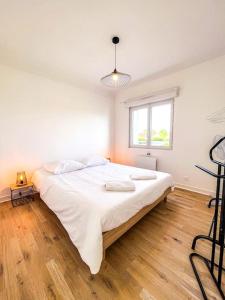 a large white bed in a room with a wooden floor at Le Convivial • Stationnement Facile • Paisible in Déols