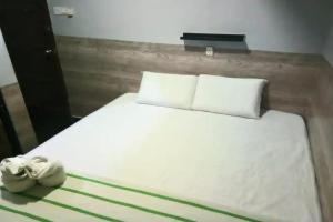 a bed with white sheets and two towels on it at Dongfang Motel in Kuala Lumpur