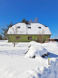 a snow covered yard with a green house at Kõrgemäe puhketalu in Eoste