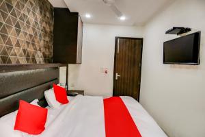 a bedroom with a bed with red pillows and a television at OYO Anshun Residency Near M2k Cinemas Rohini in New Delhi