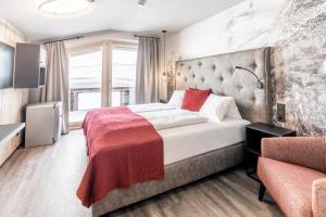 a bedroom with a large bed with a red blanket at Hotel Astrid mit Panoramapool & inklusive JokerCard in Saalbach-Hinterglemm +135 photos