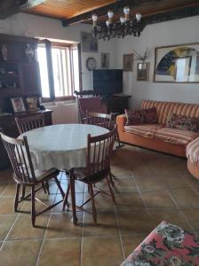 sala de estar con mesa, sillas y sofá en Appartamento vista sul lago, en Musignano