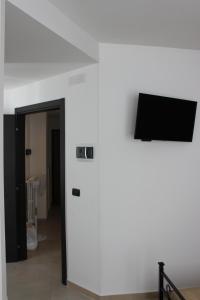 Habitación con pared blanca y TV de pantalla plana. en Poggiofranco Apartaments, en Bari