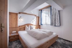 een slaapkamer met een bed met witte lakens en een raam bij Huber Apartments in Kappl +49 foto's