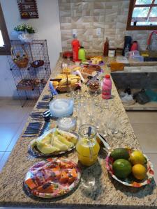 a kitchen counter with plates of food and fruit on it at Pousada e Pesque e Pague Vista Alegre in Paty do Alferes