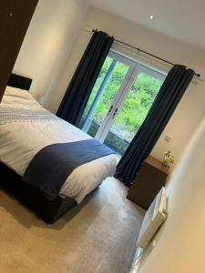 a bedroom with a bed and a large window at Contemporary apartment Great Location with private carpark in Keighley