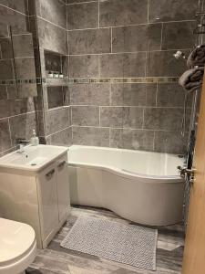 a bathroom with a tub and a toilet and a sink at Contemporary apartment Great Location with private carpark in Keighley
