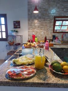 a kitchen counter with plates of food and glasses of orange juice at Pousada e Pesque e Pague Vista Alegre in Paty do Alferes