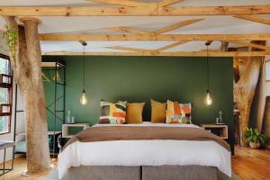 a bedroom with a large bed with a green wall at Elsewhere Treehouse and Apartment on the River in Muldersdrift