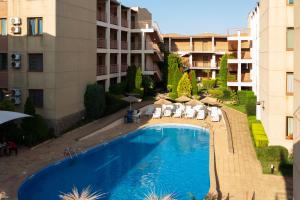a swimming pool with chairs and umbrellas next to a building at Частен апартамент в затворен комплекс in Sinemorets