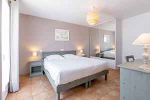 a bedroom with a large white bed and a mirror at Villa Sainte Anne in Porquerolles