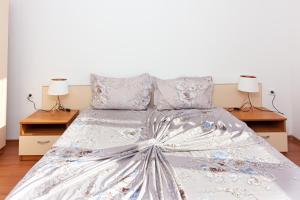 a bed with a silver bedspread and two lamps at Частен апартамент в затворен комплекс in Sinemorets +8 photos