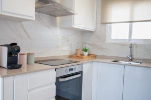 a white kitchen with a stove and a sink at Ítaca Apartments Peñiscola - Cerromar in Peniscola