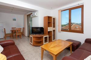 a living room with a couch and a tv and a table at Частен апартамент в затворен комплекс in Sinemorets