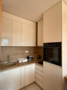 cocina con armarios blancos, fregadero y microondas en Apartman 21 Vila Elsa III Zlatibor en Zlatibor