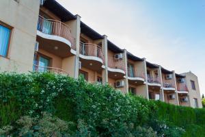 an apartment building with balconies and a hedge at Частен апартамент в затворен комплекс in Sinemorets