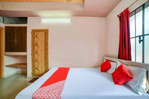 um quarto com uma cama com almofadas vermelhas e brancas em Flagship Hotel Mayur em Dalaigaon