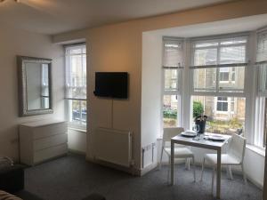 a living room with a table and chairs and windows at Newly Renovated Modern Studio Apartment in Penzance