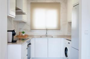 a white kitchen with a sink and a dishwasher at Ítaca Apartment Peñiscola in Peñíscola +19 photos