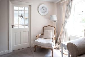 Apple Cottage -- Luxury Stay @ Bellingham Castle في كاستيلبيلينغهام: غرفة بيضاء مع كرسي وساعة على الحائط