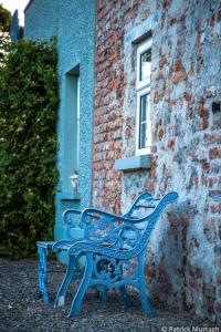 Apple Cottage -- Luxury Stay @ Bellingham Castle في كاستيلبيلينغهام: جلسة على كرسي ازرق بجانب مبنى من الطوب