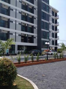 un estacionamiento frente a un edificio alto en Promsook Apartment en Bangsaen