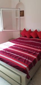 ein Bett mit roten Kissen im Schlafzimmer in der Unterkunft domaine club Evasion in Tamelalt