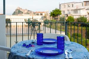 uma mesa azul com pratos e óculos azuis numa varanda em Villa dei Sogni - Aparthotel Ischia Ponte em Ischia