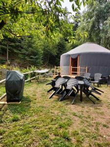 la Yourte des Bibis في Fréland: خيمة مع كراسي وطاولة في ميدان