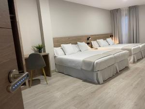 una habitación de hotel con 2 camas y una silla en URBAN Pensión, en Melide