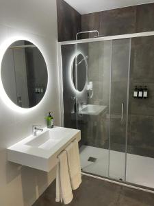 a bathroom with a sink and a shower and a mirror at URBAN Pensión in Melide