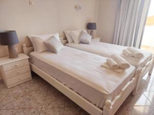 a bedroom with two beds with white sheets and towels at Agia Roumeli Hotel in Agia Roumeli