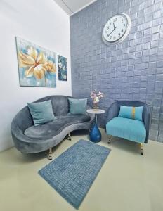 uma sala de estar com um sofá, uma cadeira e um relógio em Cozy n Quiet home near to BKE Highway n Kulim High Tech Park em Lunas