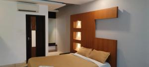 a bedroom with a bed with a wooden headboard at HOTEL AL AMANA TOWER in Kondotti