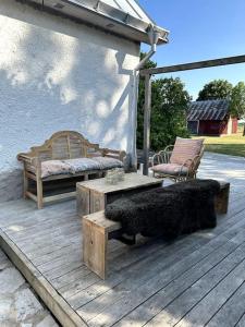 una terraza de madera con 2 bancos y una mesa en Vackert kalkstenshus på Gotland 