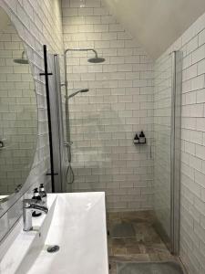 baño blanco con ducha y lavamanos en Vackert kalkstenshus på Gotland 