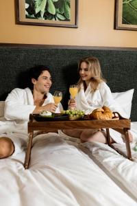 a man and woman in bed with a tray of food and drinks at Verno House in Budapest