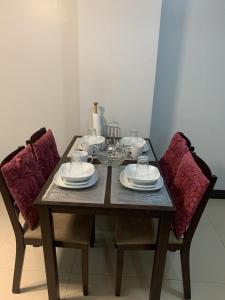 a wooden table with two chairs with plates and bowls at 1BR Condo at Montecito Newport City Residential Resort across NAIA and Marriott Hotel in Manila