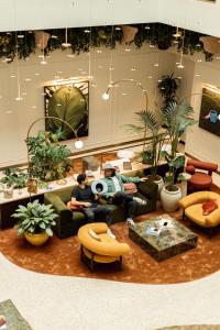 two men sitting on couches in a room with plants at Verno House in Budapest