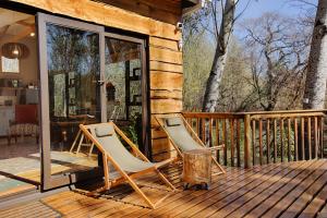 zwei Stühle auf einem Deck in einer Hütte in der Unterkunft Elsewhere Treehouse and Apartment on the River in Muldersdrift