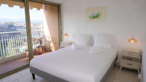 1 Schlafzimmer mit einem weißen Bett und einem Balkon in der Unterkunft Cannes Marina, T3 vue Mer, Piscine, By Palmazur in Mandelieu-la-Napoule
