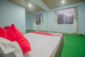Schlafzimmer mit einem Bett mit roten Kissen und einem Fenster in der Unterkunft OYO Brikcha Mukhia Home Stay in Pelling