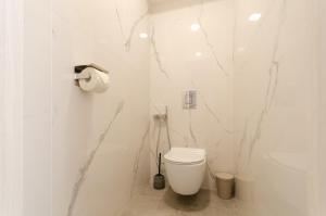 a white bathroom with a toilet and marble walls at Great Apartment 1 in Chişinău +17 photos