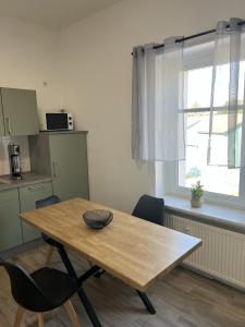 a wooden table and chairs in a kitchen with a window at Apartment 2 - Haus Lausitzring in Annahütte