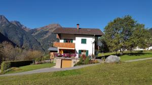 a white house with a balcony and mountains in the background at Haus Salzmann in Sankt Gallenkirch